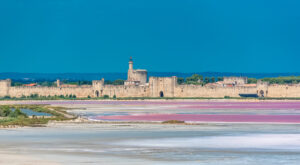 Mittelalterliche Stadtmauer von Aigues-Mortes – mit rosafarbenen Salinen unter blauem Himmel.