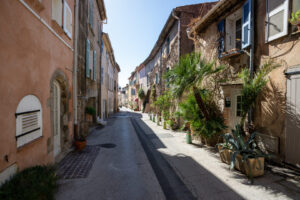 Schmale Gasse in der Altstadt von Cogolin mit alten Fassaden und mediterranen Pflanzen