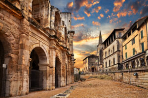 Abendstimmung am Amphitheater von Arles mit historischem Stadthintergrund.