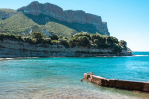 Cap Canaille über einer Badebucht bei Cassis mit klarem türkisblauem Wasser