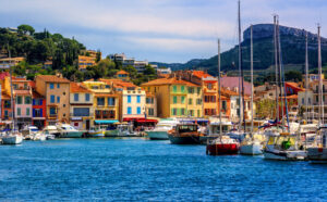 Hafen von Cassis mit bunten Häusern, Segelbooten und Felsen im Hintergrund