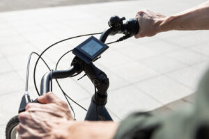 Blick auf den Lenker eines E-Bikes mit digitalem Display und Händen an den Griffen