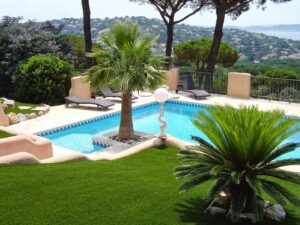 Pool mit Sonnenliegen und Palmen