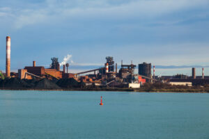 Industriehafen von Fos-sur-Mer am Golf von Fos mit Schornsteinen, Werksanlagen und ruhigem Wasser im Vordergrund