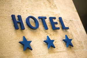 Blauer Hotel-Schriftzug mit drei Sternen an einer hellen Steinfassade