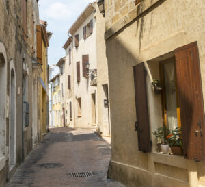 Schmale Gasse im historischen Zentrum von Istres mit hellen Fassaden und Fensterläden