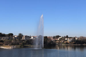 Jet d’eau auf dem Étang de l’Olivier in Istres mit Häusern am Ufer