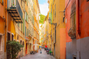 Reisende mit Rollkoffer in einer schmalen Altstadtgasse von Nizza.