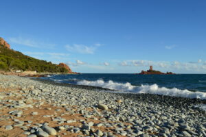Kiesstrand bei Le Dramont mit Brandung, roten Estérelfelsen und der Île d’Or