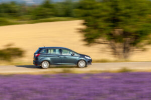 Auto auf einer Landstraße zwischen Feldern in der Landschaft des Luberon
