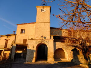 Uhrturm mit Torbogen im historischen Ortskern von Lurs im warmen Abendlicht