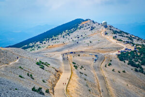 Serpentinen der Gipfelstraße am Mont Ventoux mit Radarkuppel und Parkplatz in karger Steinlandschaft
