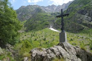 Kreuz am Wanderweg in einem grünen Hochtal des Écrins-Massivs