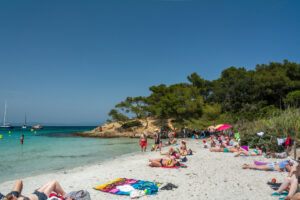 Plage d’Argent auf Porquerolles mit hellem Sand, Badegästen, Pinien und türkisfarbenem Wasser