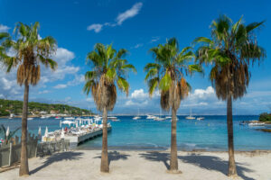 Plage de la Garoupe am Cap d’Antibes mit Palmen, Sandstrand, Booten und blauem Meer