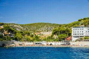Plage du Bestouan in Cassis mit Badegästen und dem Hôtel de la Plage Mahogany am rechten Bildrand