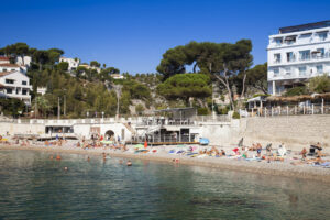 Plage du Bestouan in Cassis mit Kiesstrand, Badegästen und Pinien