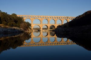 Pont du Gard im warmen Abendlicht mit Spiegelung auf dem Gardon