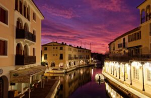 Abendstimmung an einem Kanal in Port Grimaud mit beleuchteten Arkaden und violettem Himmel