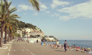 Kieselstrand an der Promenade des Anglais mit Badegästen und Blick Richtung Altstadt von Nizza