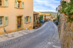 Abfallende Gasse mit pastellfarbenen Häusern in der Altstadt von Ramatuelle