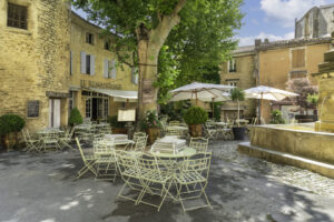 Restaurantterrasse in Gordes mit Platanen, Brunnen und Natursteinfassaden