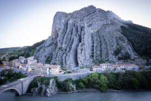 Rocher de la Baume in Sisteron mit Häusern, Steinbrücke und Fluss am Fuß des markanten Felsens