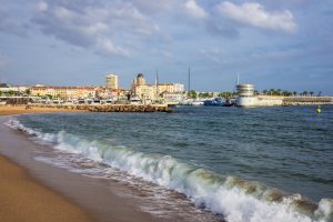Plage du Veillat in Saint-Raphaël mit Wellen, Hafen und Basilika im Hintergrund