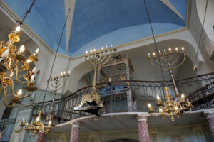 Innenraum der Synagoge von Carpentras mit Leuchtern, Empore und blauem Gewölbe