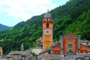 Fassade der Collégiale Notre-Dame de l’Assomption in Tende vor grünen Berghängen