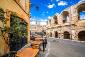 Caféterrasse in Arles mit römischem Amphitheater und Altstadtgasse
