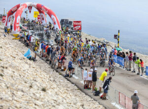Tour de France am Mont Ventoux: Fahrerfeld und Zuschauer an der Gipfelstraße unter Sponsorbogen