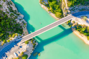 Luftaufnahme der Brücke über das türkisfarbene Wasser am Eingang der Verdonschlucht