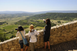 Wanderer auf einem felsigen Aussichtspunkt über der Landschaft des Luberon