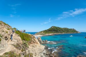 Wanderer auf dem Küstenweg bei Ramatuelle mit Blick auf türkisblaues Meer und Felsküste