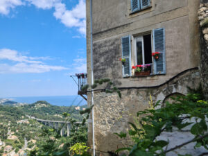 Provenzalisches Haus mit Balkon in Gorbio, dahinter das Mittelmeer.