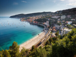 Zug an der Küste von Villefranche-sur-Mer mit Strand, Bucht und Altstadt